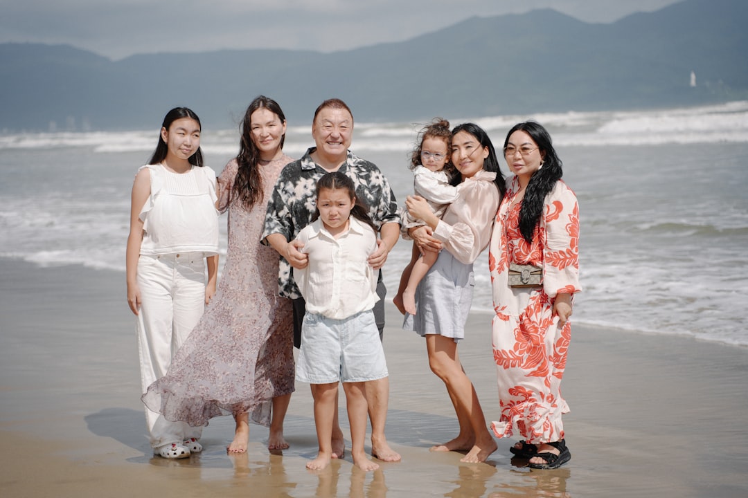 A multi-generational family poses on a beach.