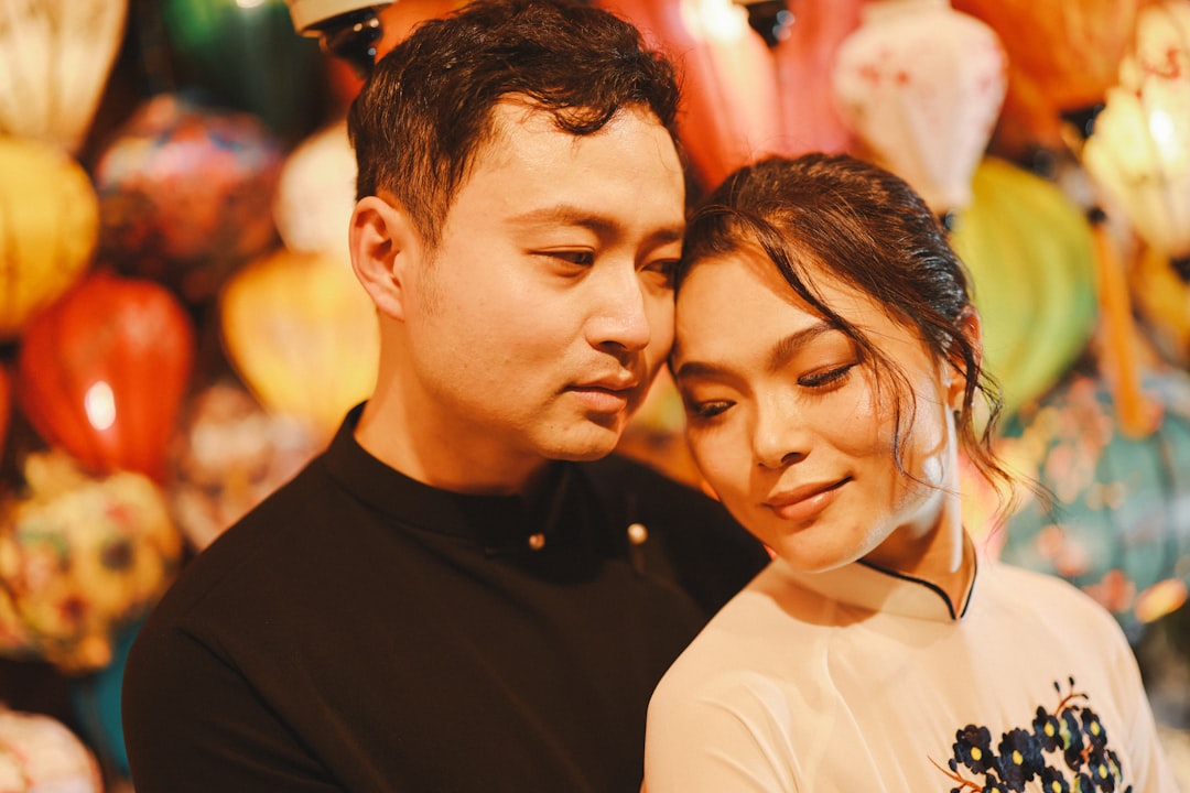 Couple embracing amidst colorful lanterns at night.